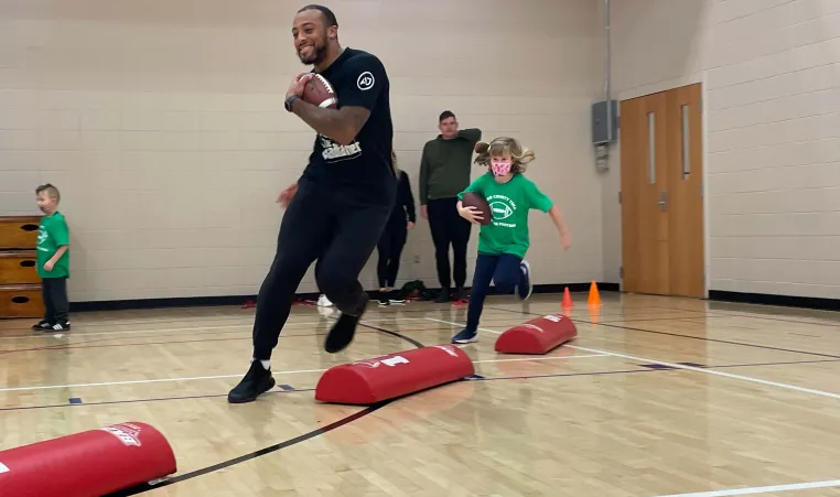 Packers' Running Back AJ Dillion with Y flag football participant