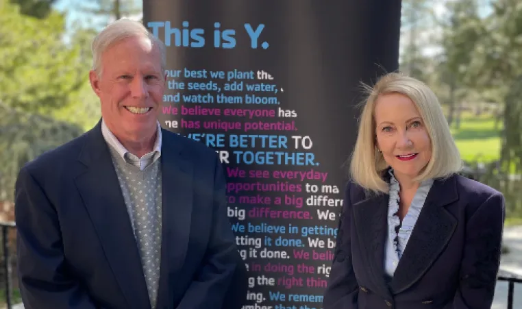 Jackie and Steve Kane standing in front of a YMCA banner.