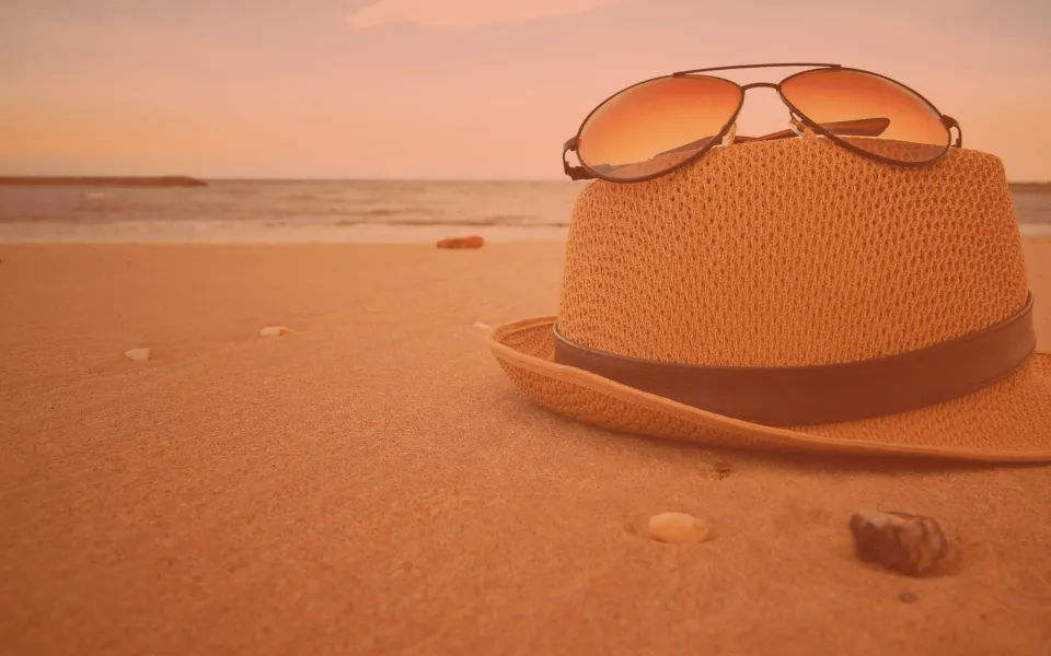 Beach with a sun hat and sunglasses in the foreground.